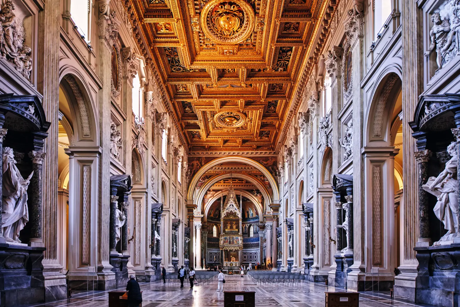 Magnificent interior of an ornate historic cathedral with a golden ceiling.