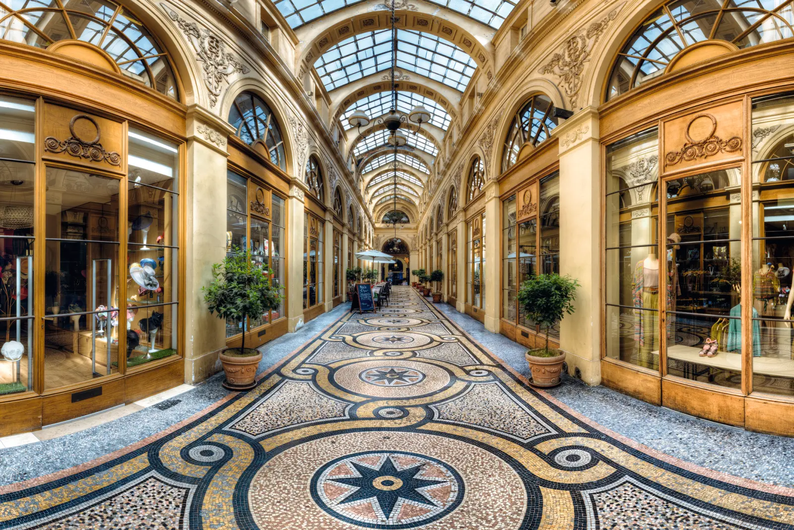 Passage à arcades avec verrière, boutiques élégantes et carrelage orné.