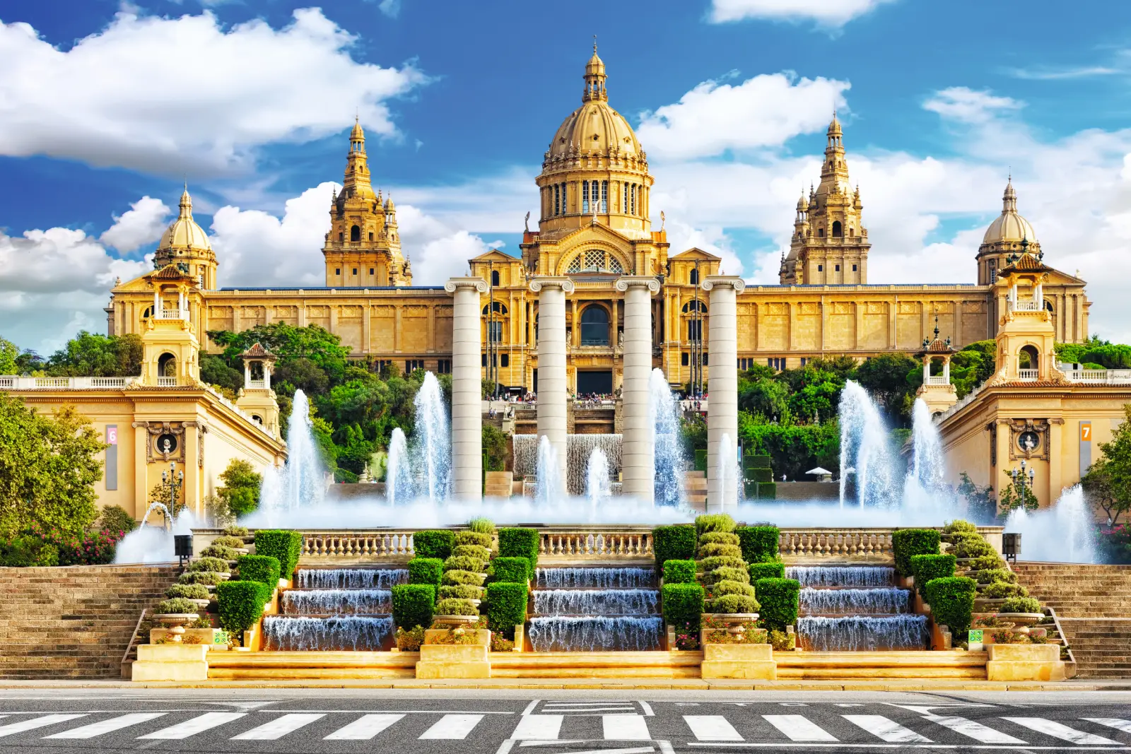 Bâtiment historique avec fontaine et escaliers sous un ciel bleu.