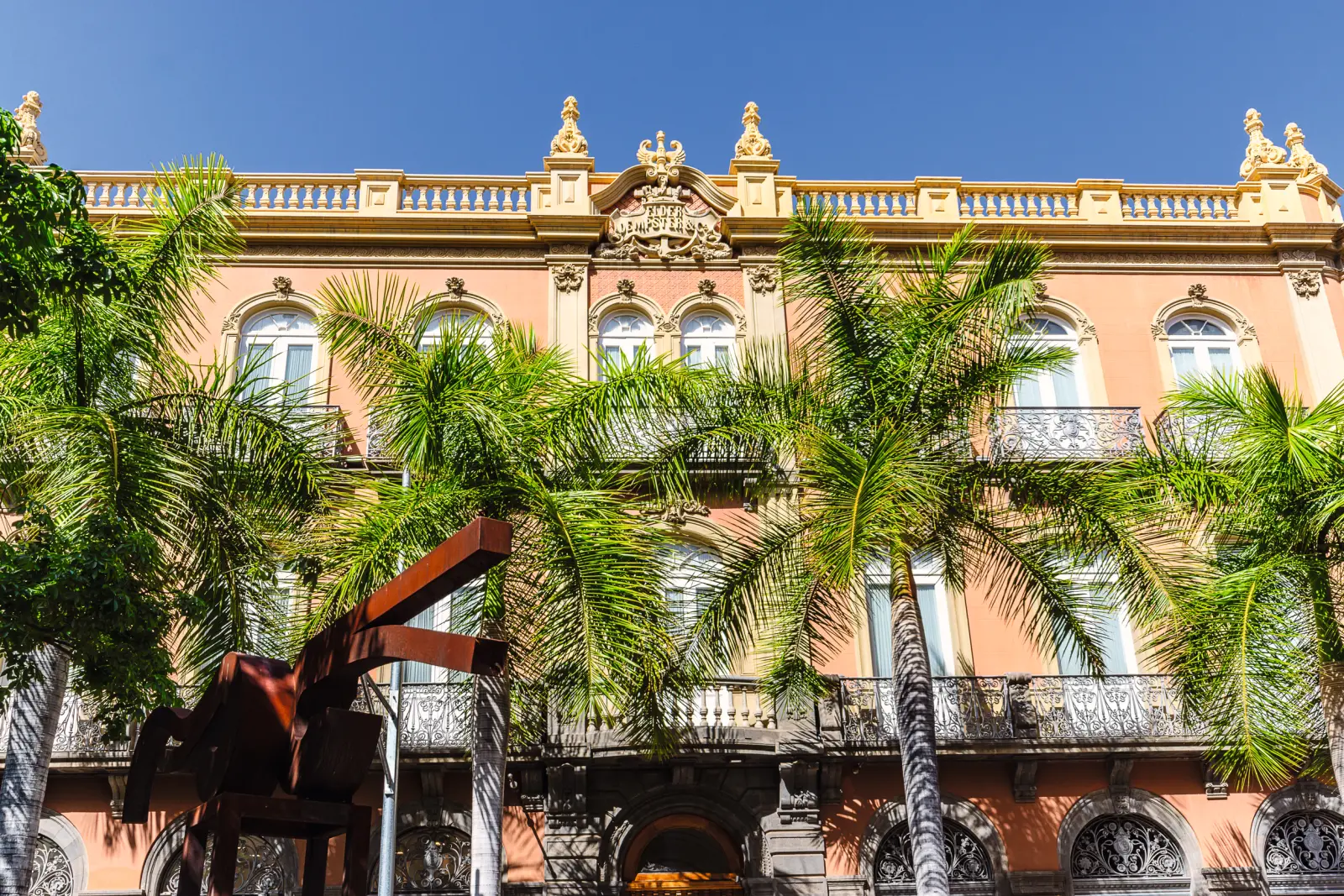 Edificio storico con palme in primo piano e cielo sereno.