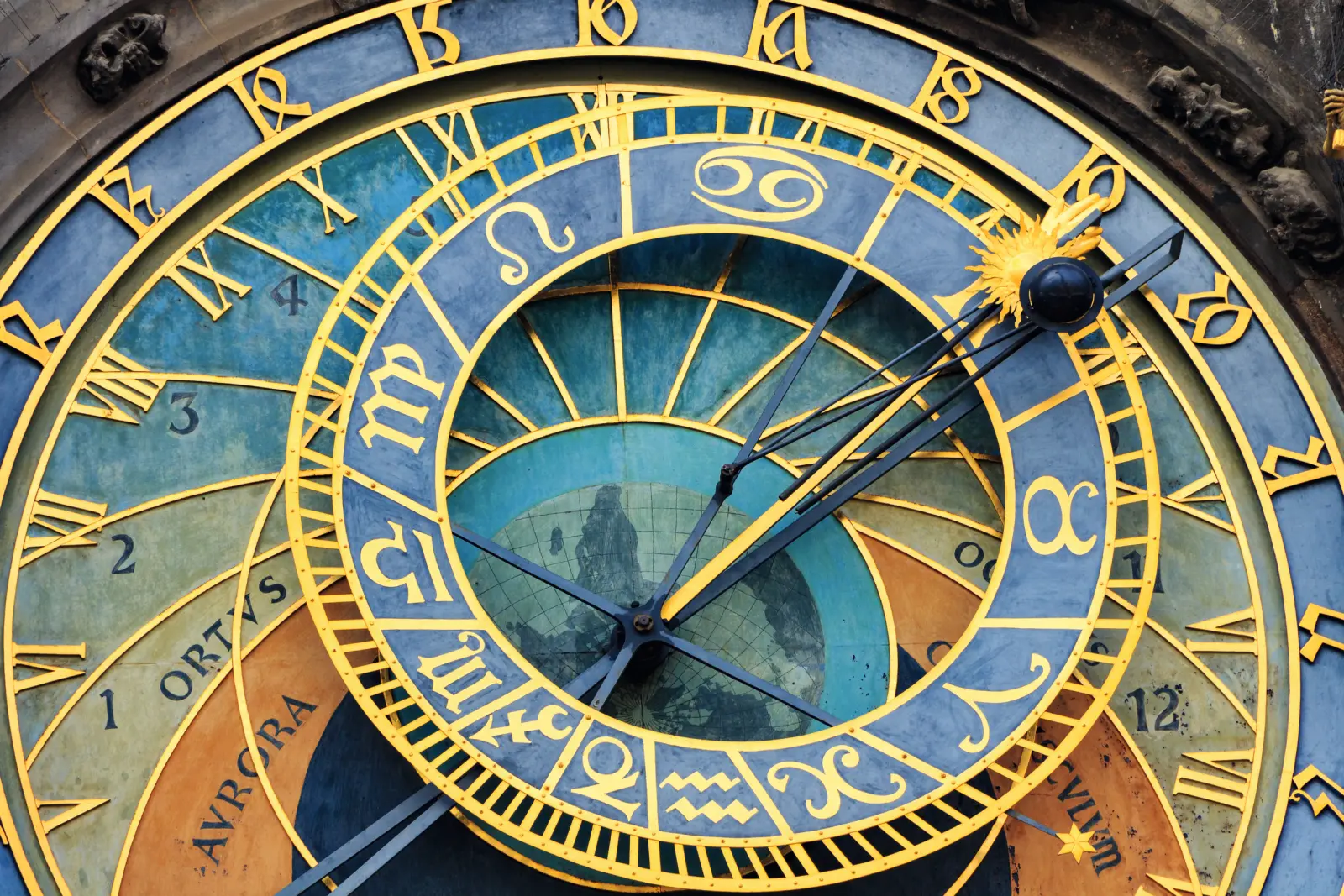 Primo piano di un orologio astronomico con segni zodiacali e numeri romani.