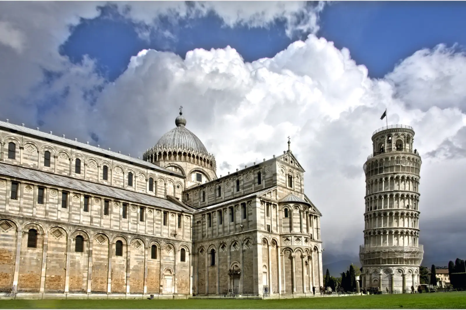Cathedral and Leaning Tower of Pisa against a cloudy sky.