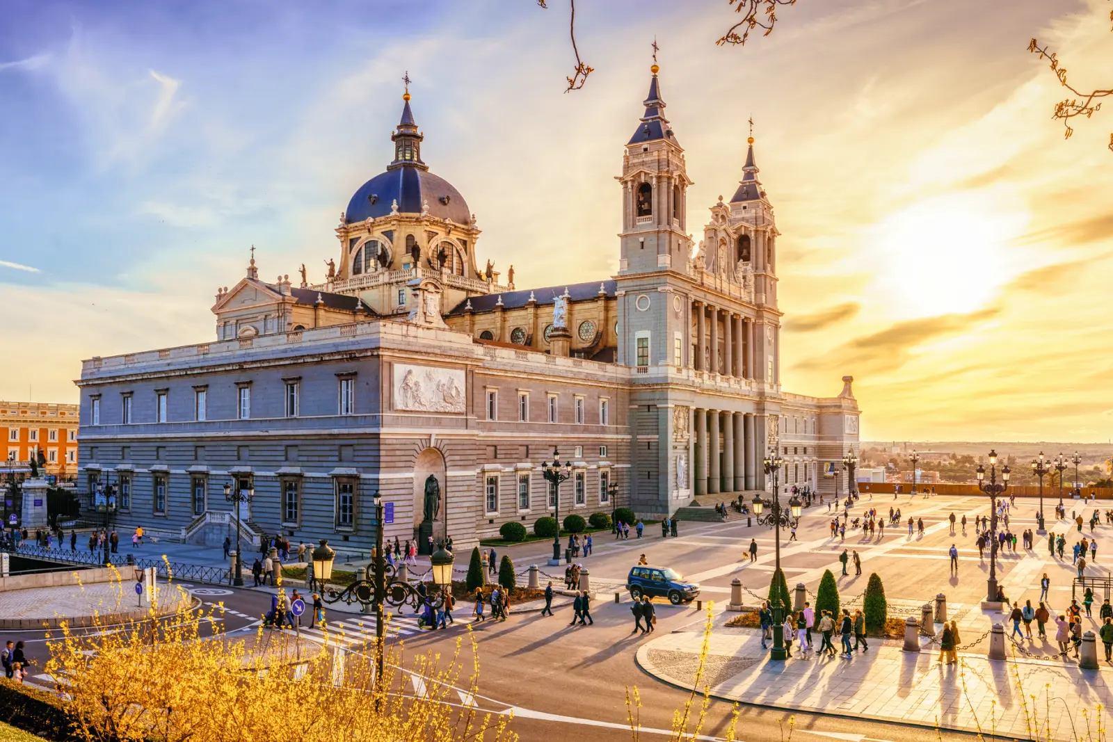 La cattedrale dell'Almudena a Madrid al tramonto, con persone sulla piazza antistante.