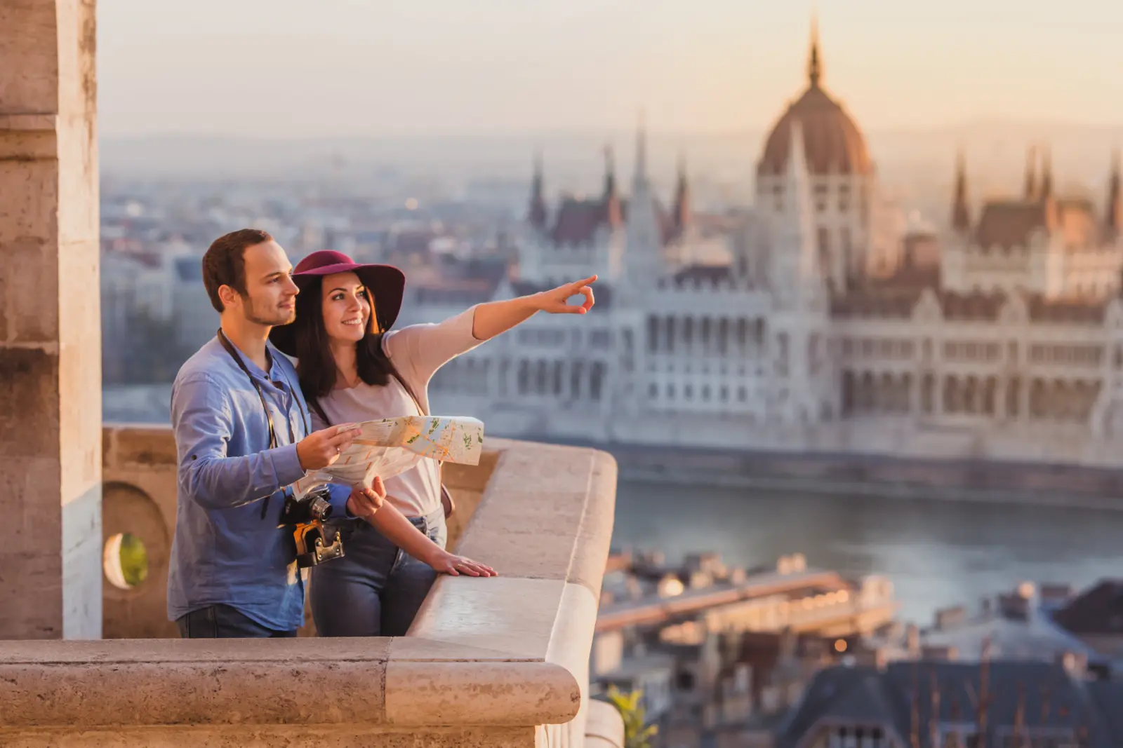 Coppia con una mappa guarda la città al tramonto, edifici sullo sfondo.