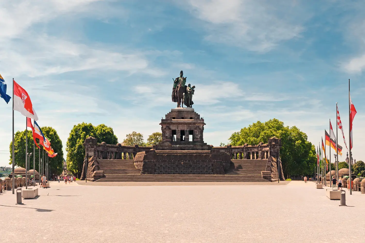 Equestrian statue at the Deutsches Eck in Koblenz with flags in the foreground.
