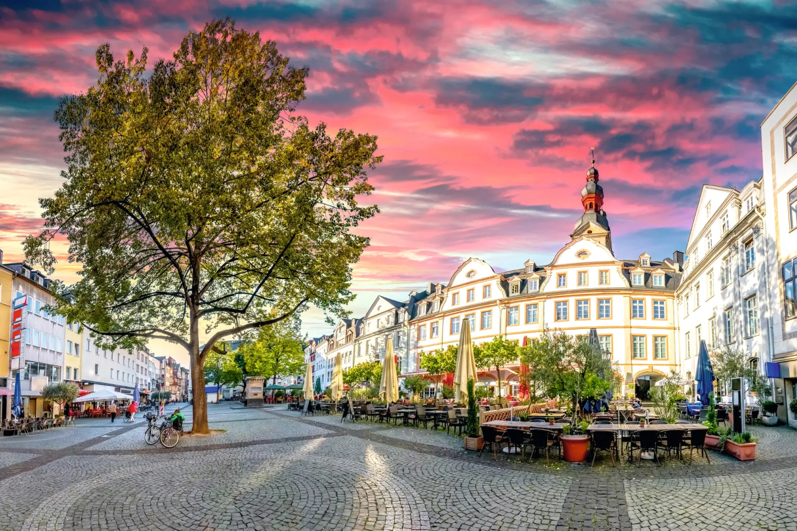 Historic market square with tables, chairs and a sky glowing in vivid sunset colours.
