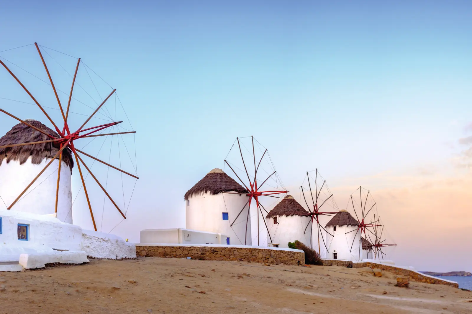 White windmills on a hill at sunset.