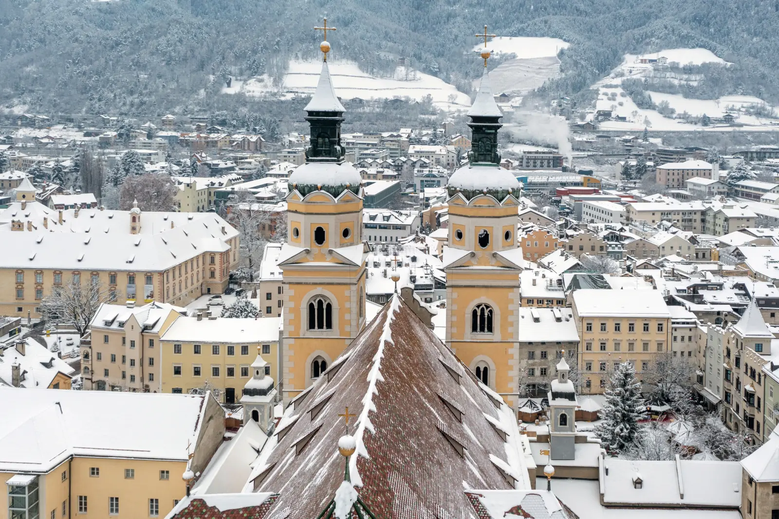 Winter view of a town with snow-covered buildings and two church towers.