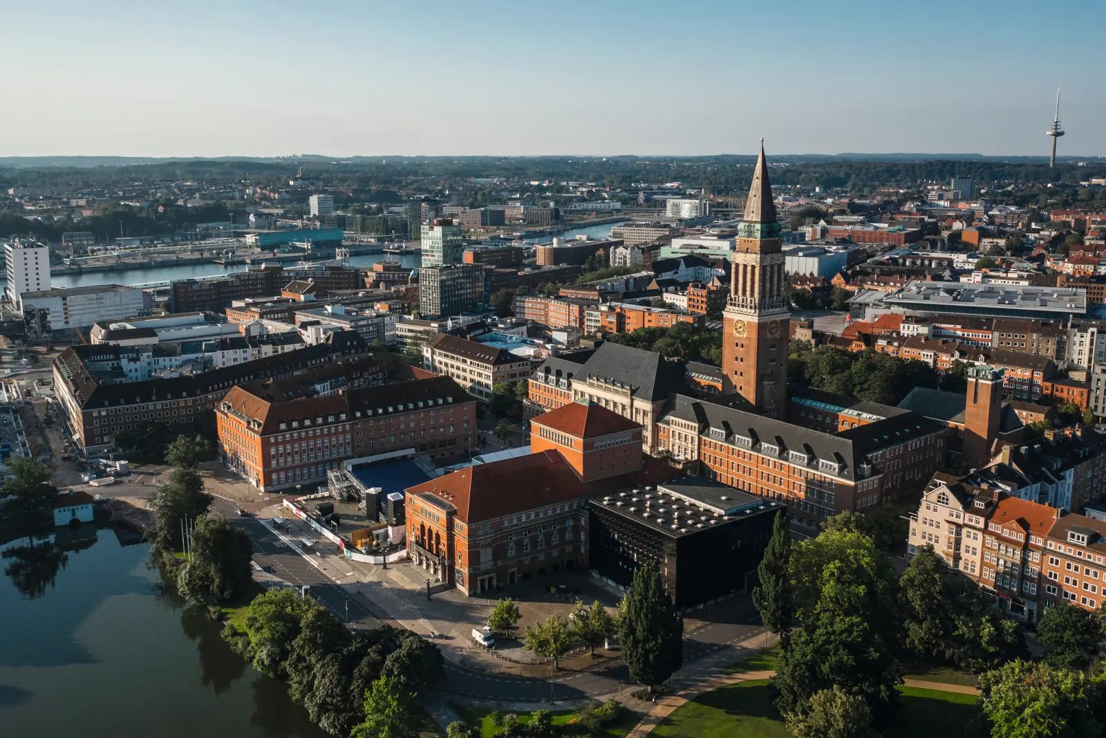 Luftaufnahme einer Stadt mit Fluss und Kirchturm im Zentrum.
