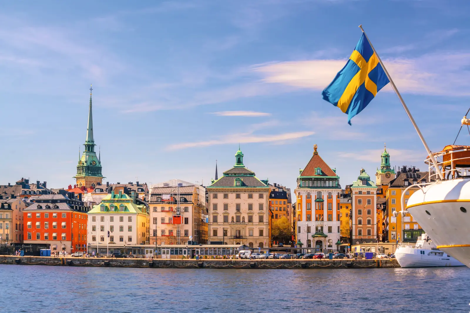 View of Stockholm with buildings and a Swedish flag in sunny weather.