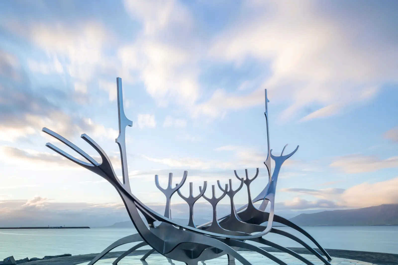 Skulptur eines stilisierten Wikingerboots am Meer unter blauem Himmel.