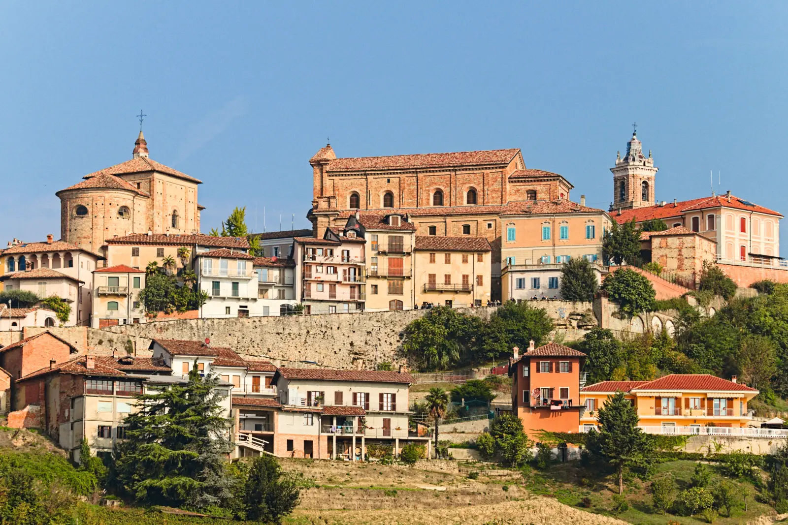 Panorama d’un paysage vallonné italien avec des bâtiments historiques.