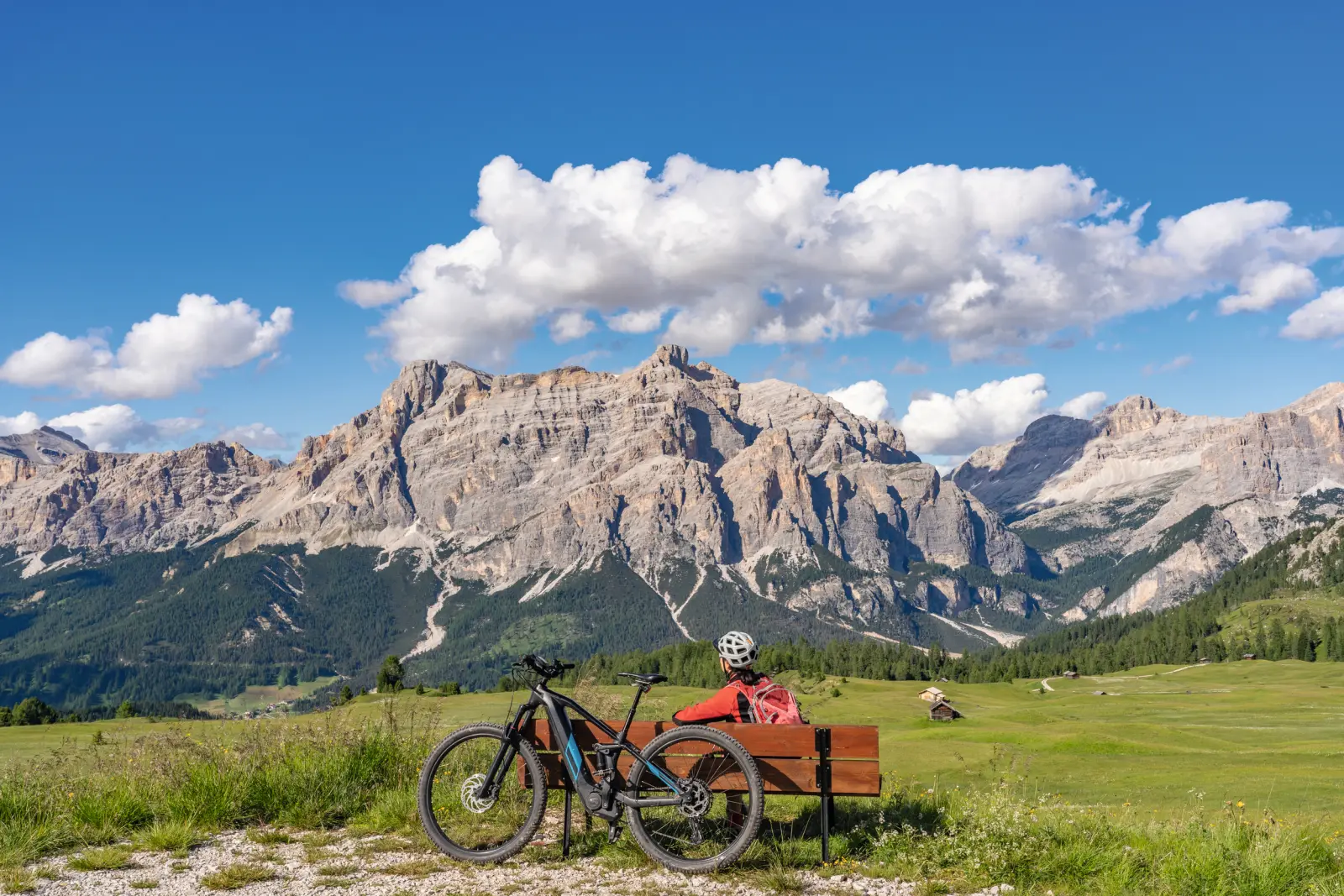 Person mit Rad genießt Bergblick auf einer Bank.