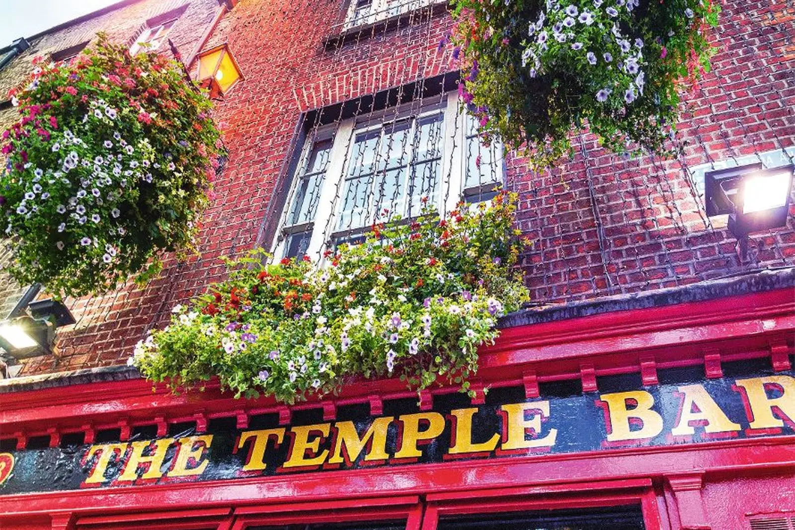 Façade du Temple Bar avec des murs de briques rouges et des fleurs en pleine floraison.