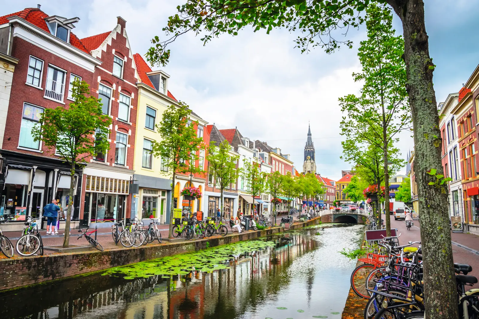 Row of houses along a canal with bicycles and trees on a cloudy day