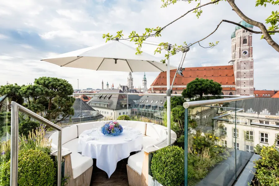 Table fleurie sous un parasol sur la terrasse, vue sur la Frauenkirche, hôtel Bayerischer Hof.