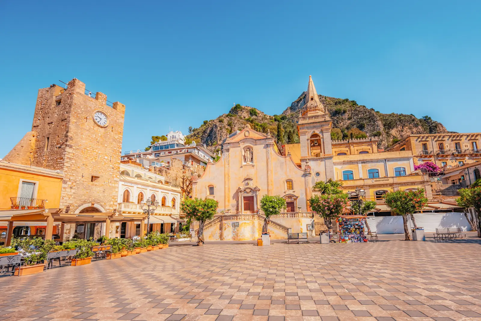Historic square with buildings and a tower under a blue sky.