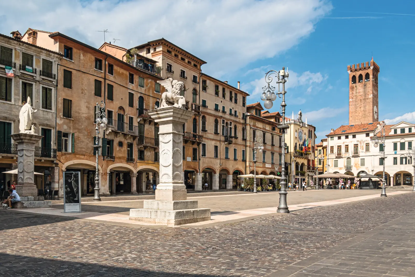 Historischer Platz mit Statuen und Turm bei Sonnenschein.
