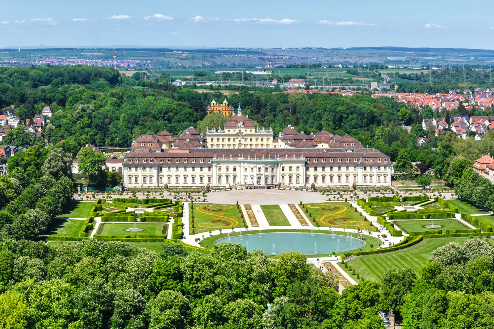 Veduta aerea di un grande castello con giardini simmetrici e fontane.