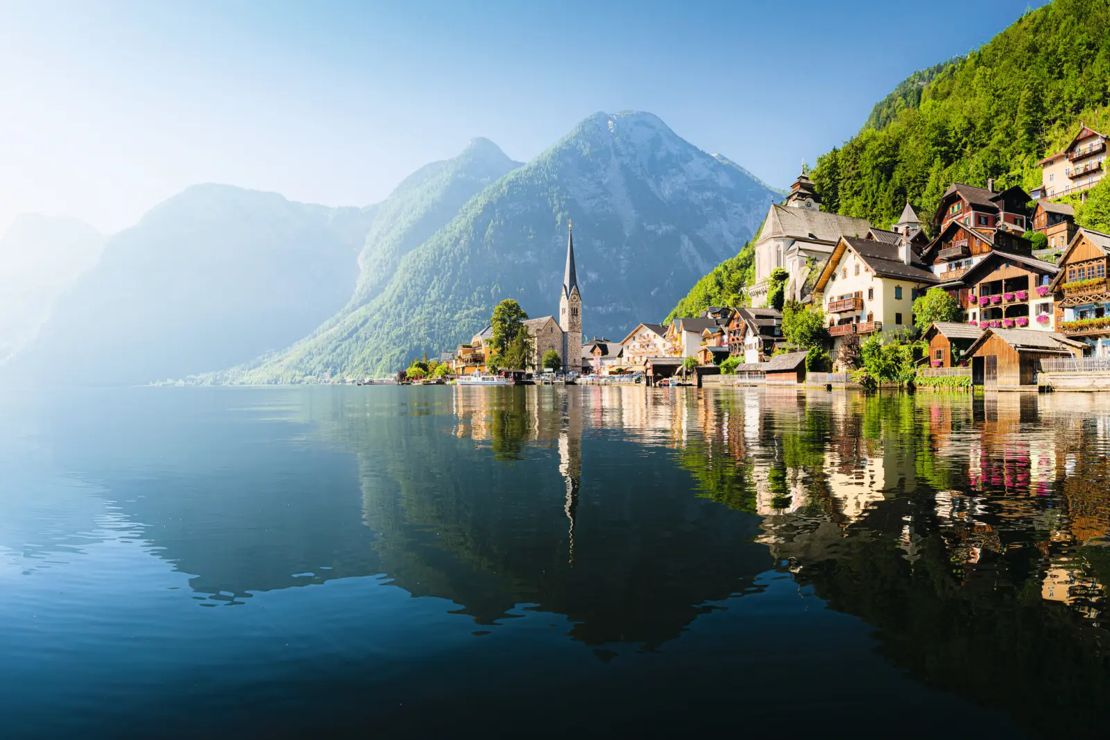 Mountain village by a lake with a church and houses in the sunshine.