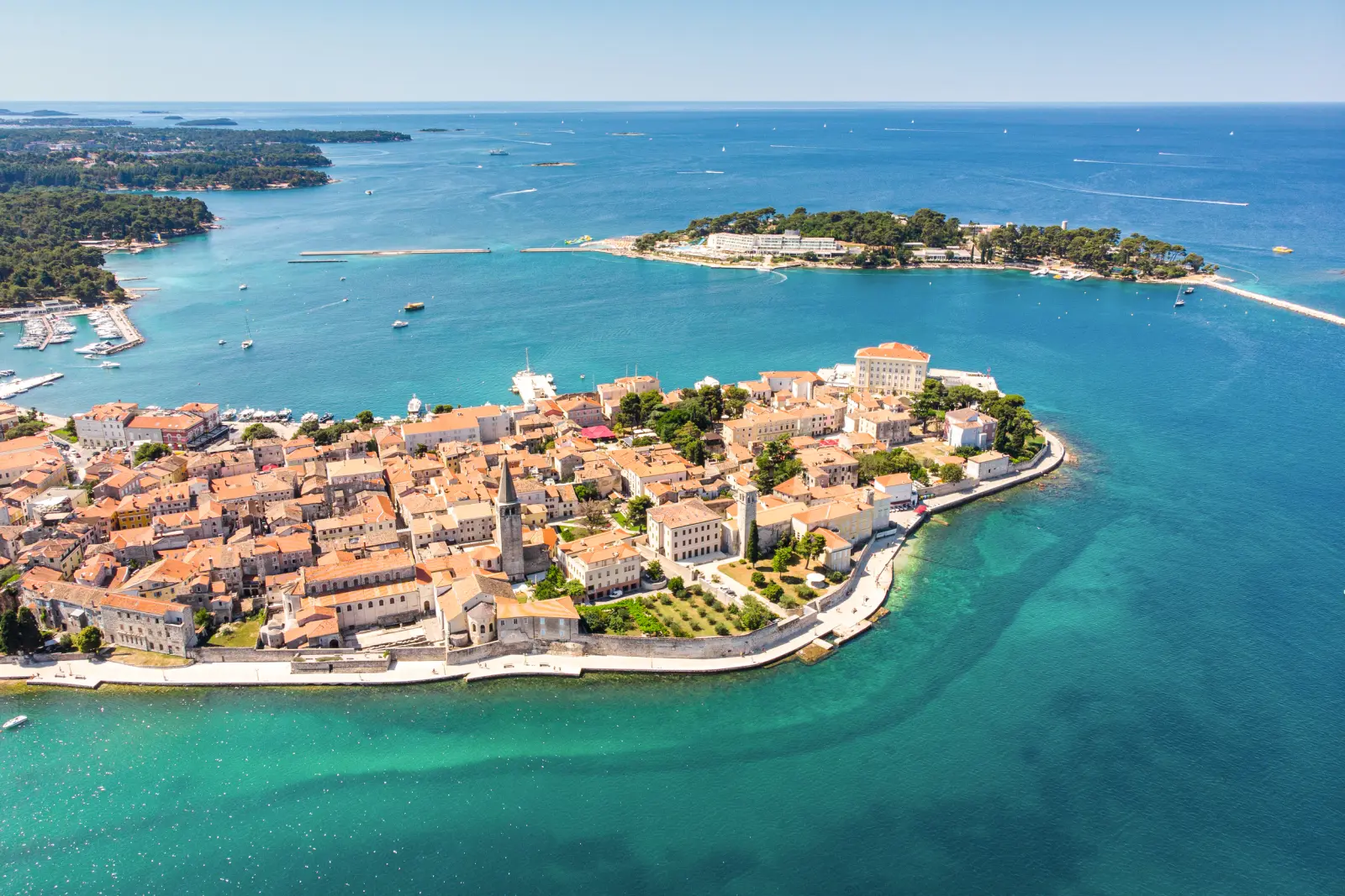 Vue aérienne d’une ville côtière avec des bâtiments historiques et une mer bleue.