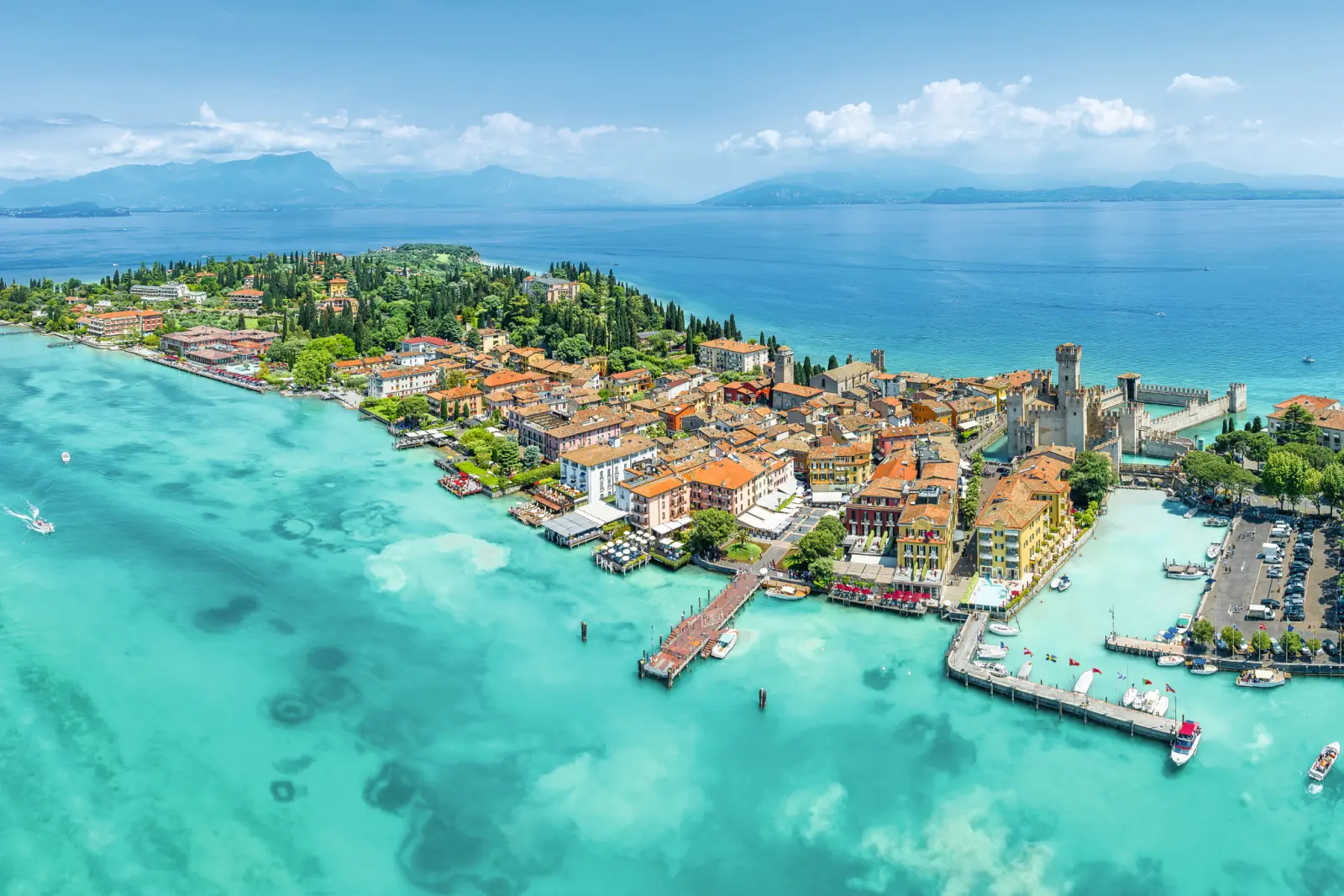 Ville côtière avec ruines de château et eau turquoise vue du ciel.