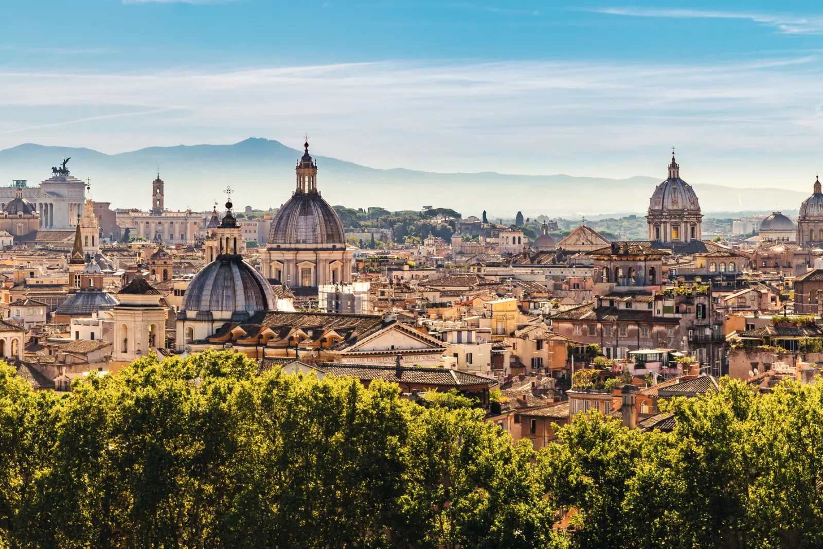 Panorama of Rome with domes and monuments under a blue sky.