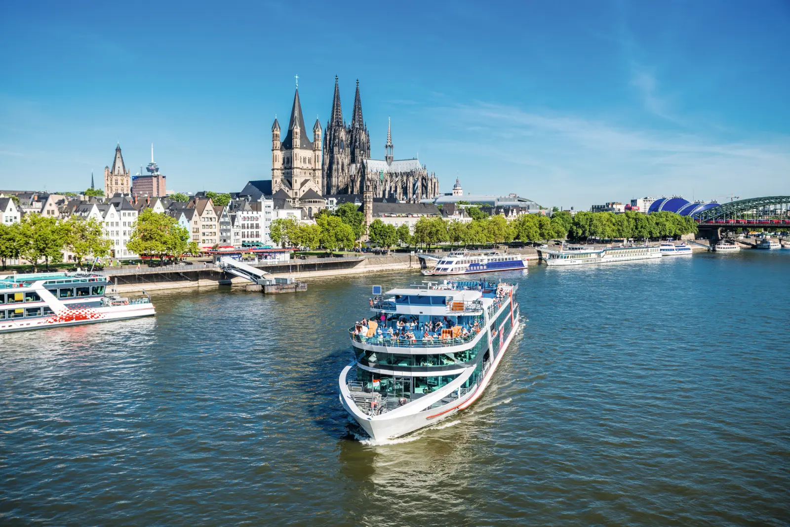 Cruise ship on the Rhine in front of Cologne Cathedral in sunny weather.