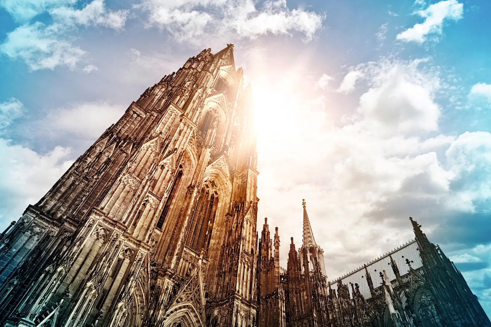 Sunshine behind a Gothic cathedral with clouds in the sky.