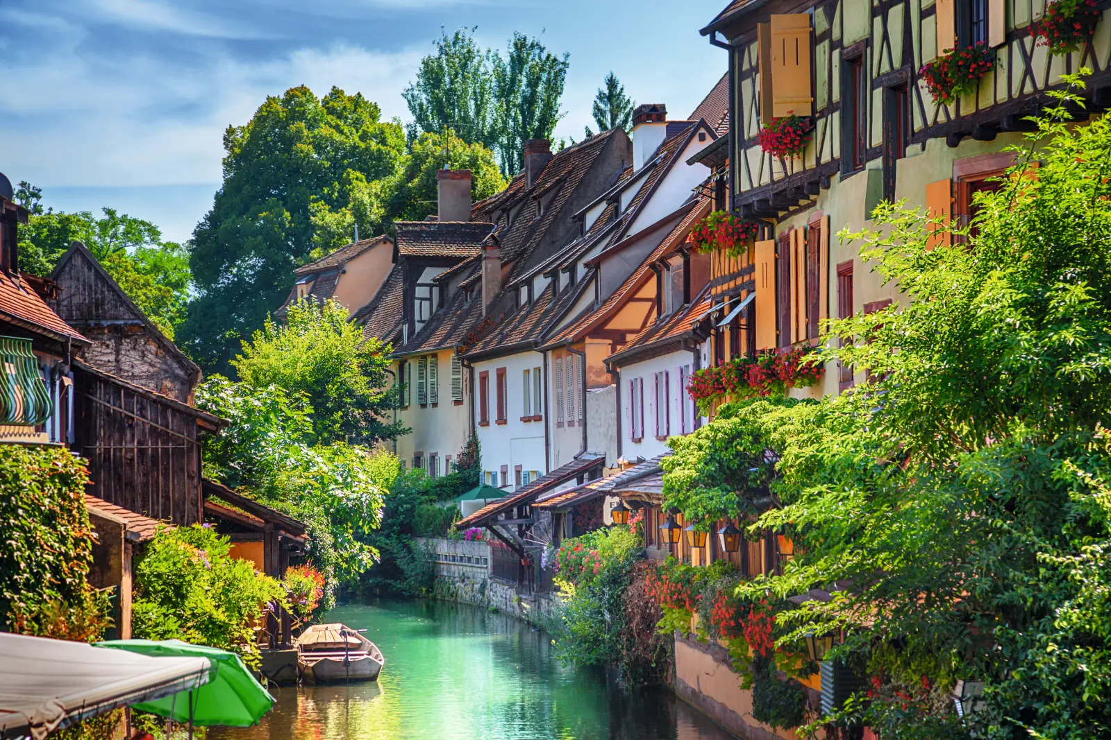Rangées de maisons le long d’un canal avec un bateau, entourées d’une verdure luxuriante.