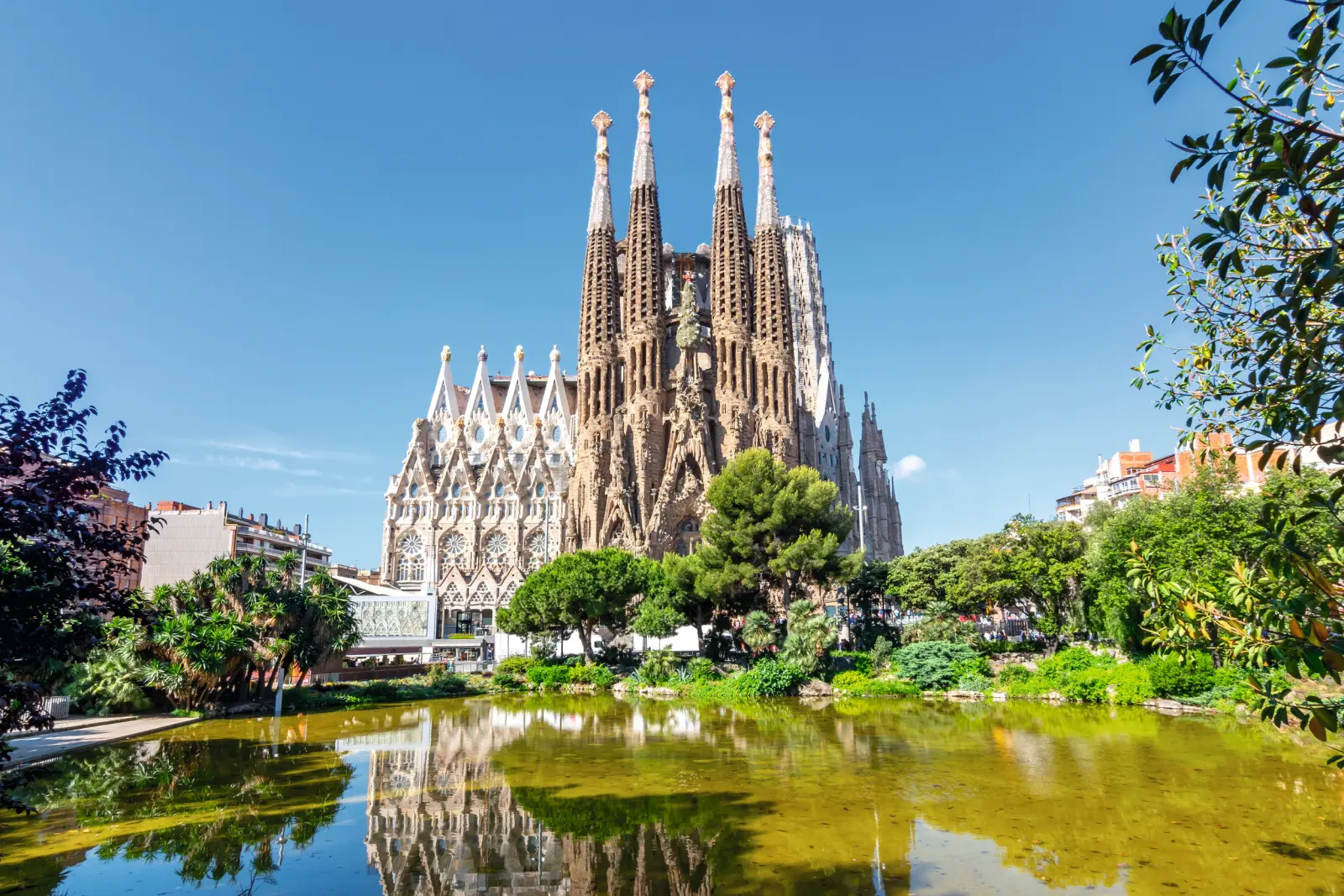 Sagrada Família a Barcellona con cielo sereno e riflesso nell'acqua.