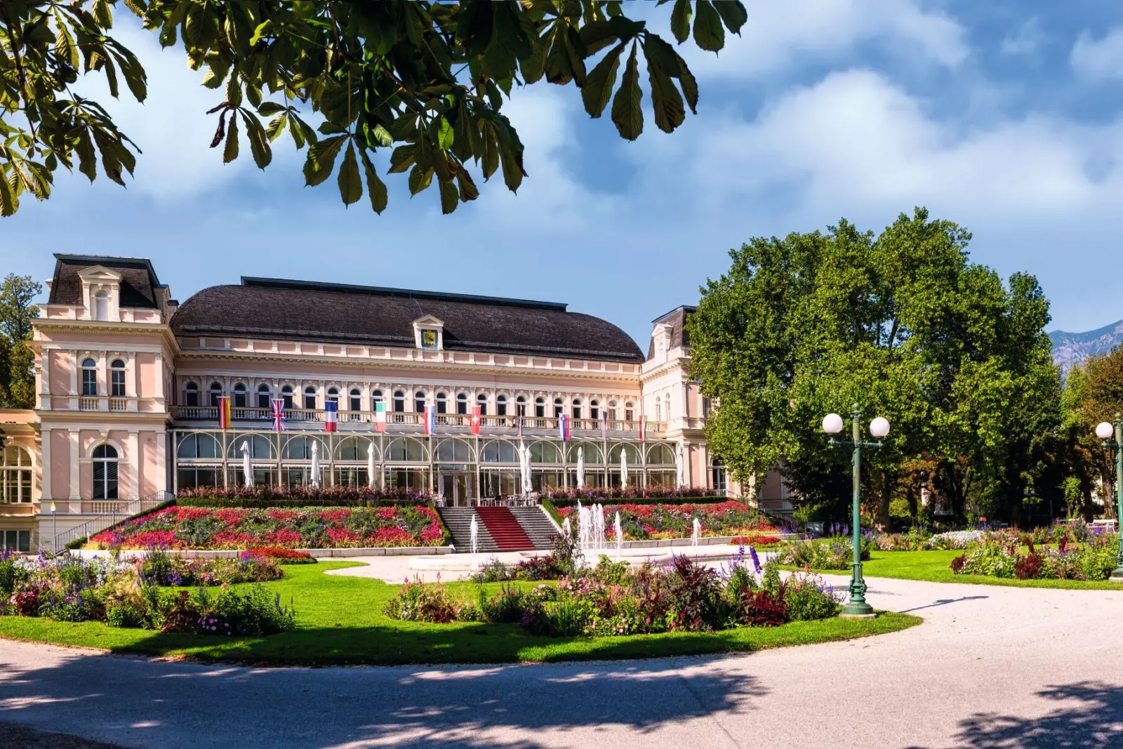 Edificio storico con giardino e aiuole fiorite.