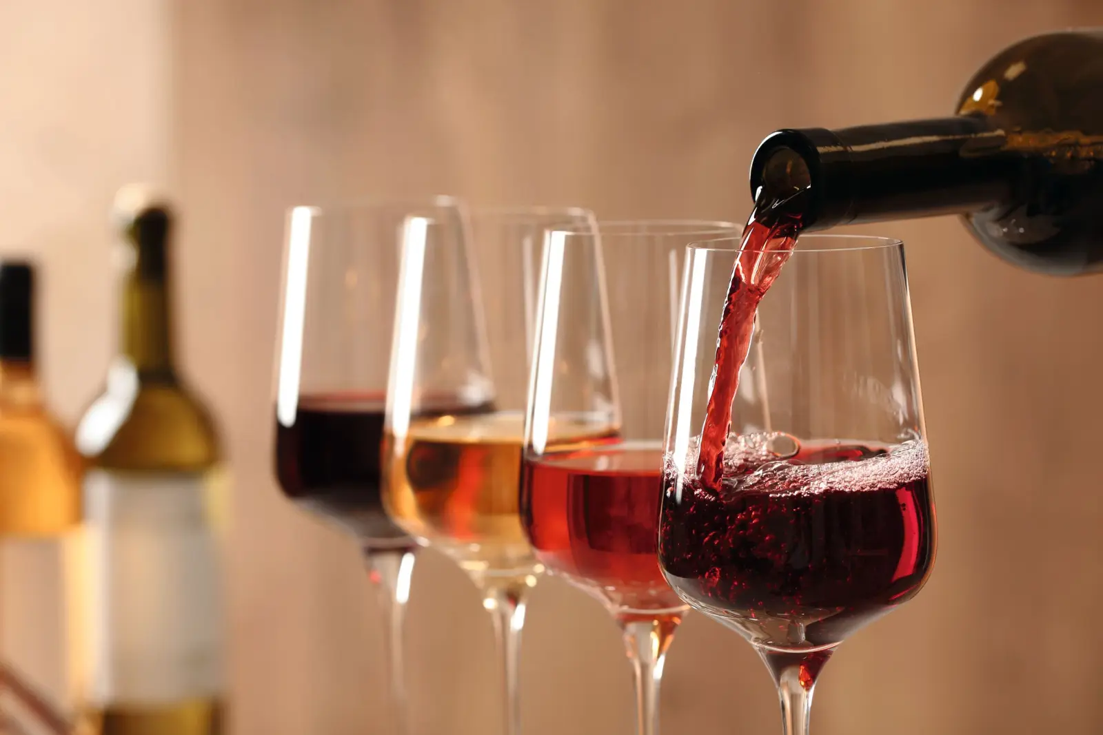 Red liquid being poured into several wine glasses.