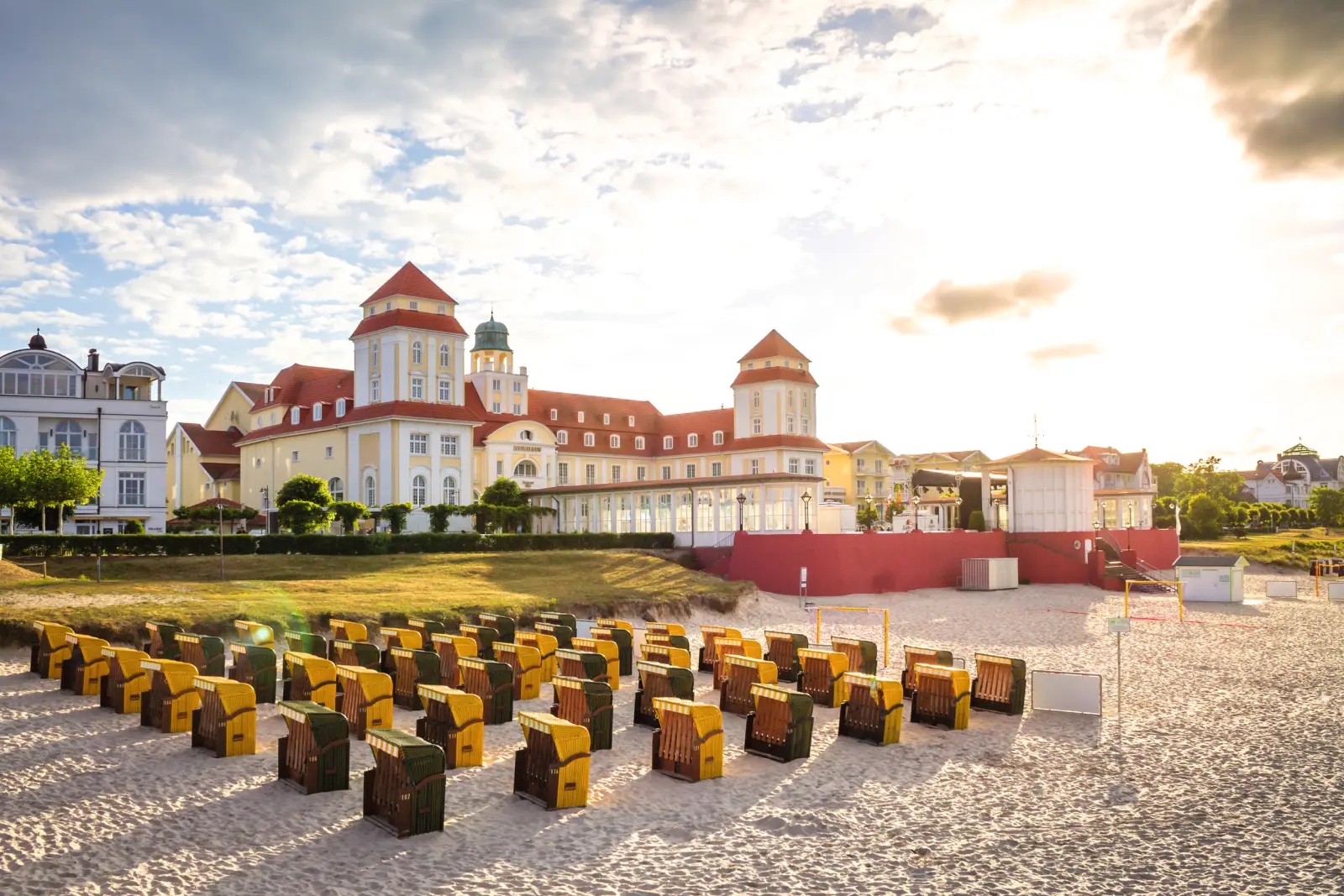 Beach chairs on a sandy beach in front of a historic building at sunset