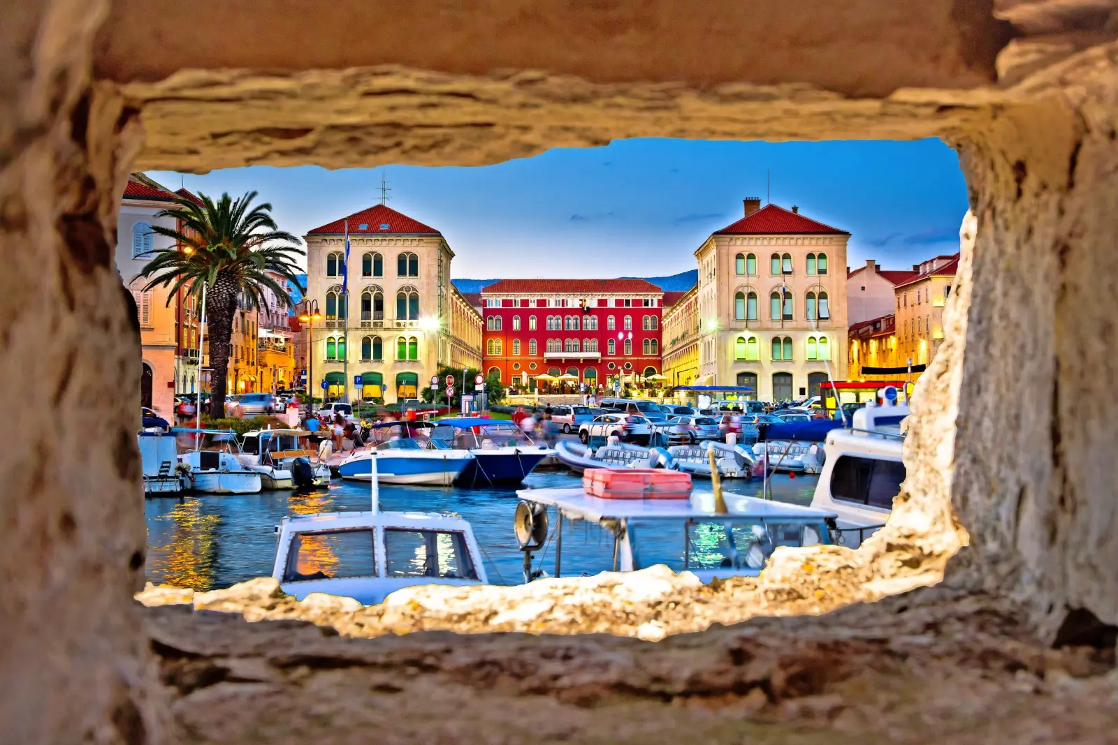 Vista sul porto con barche ed edifici storici al crepuscolo.