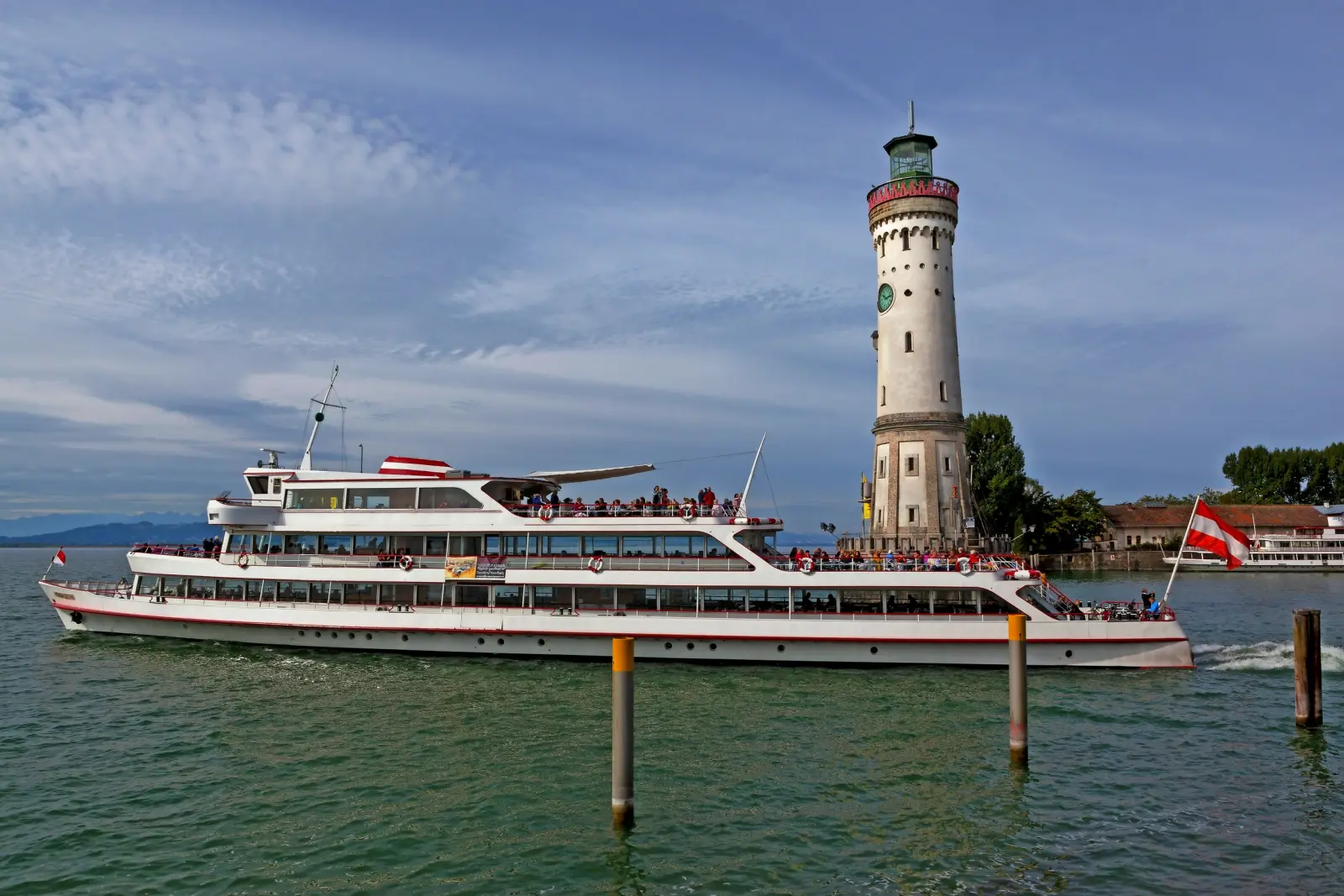 Un battello turistico passa davanti a un faro su un lago.