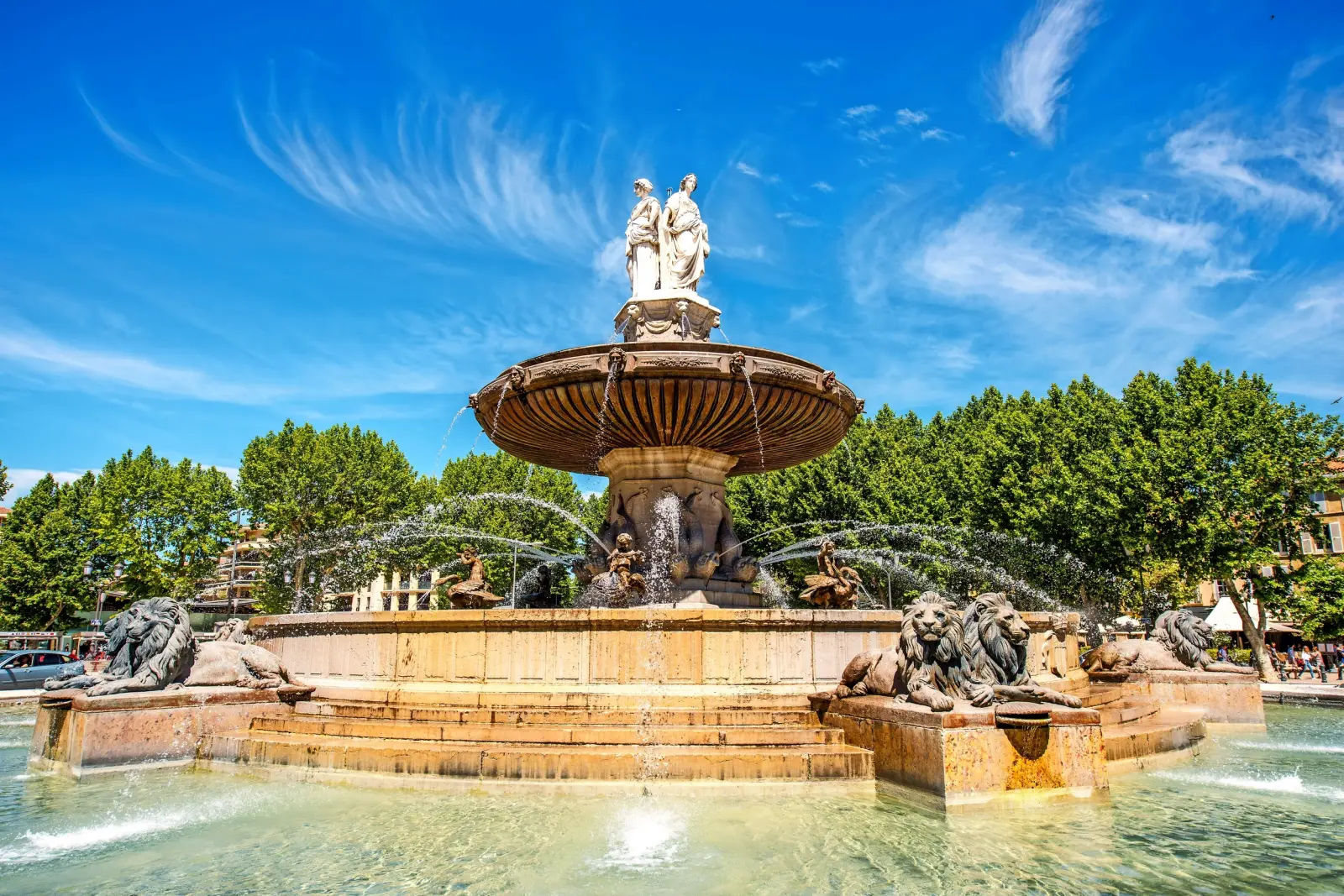 Grande fontaine artistique ornée de sculptures et de gargouilles sous un ciel bleu.