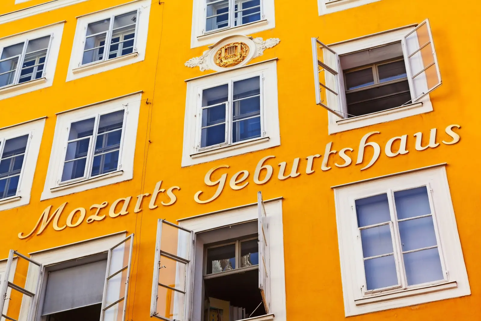 Edificio giallo con la scritta "Mozarts Geburtshaus" e diverse finestre aperte.