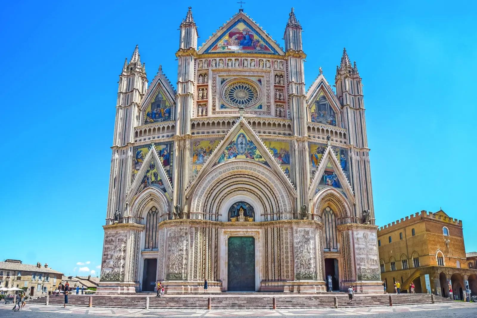 Cattedrale gotica con facciate riccamente decorate e cielo azzurro sullo sfondo.