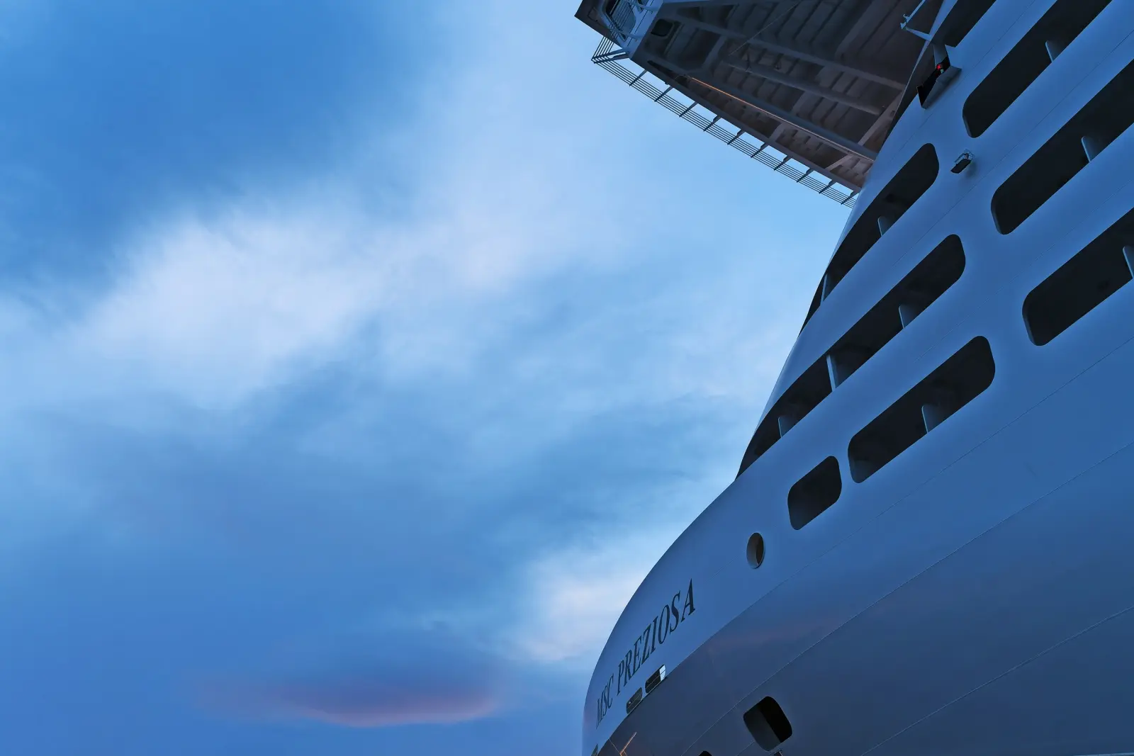 Large cruise ship in port at sunrise with a dramatic sky in the background.