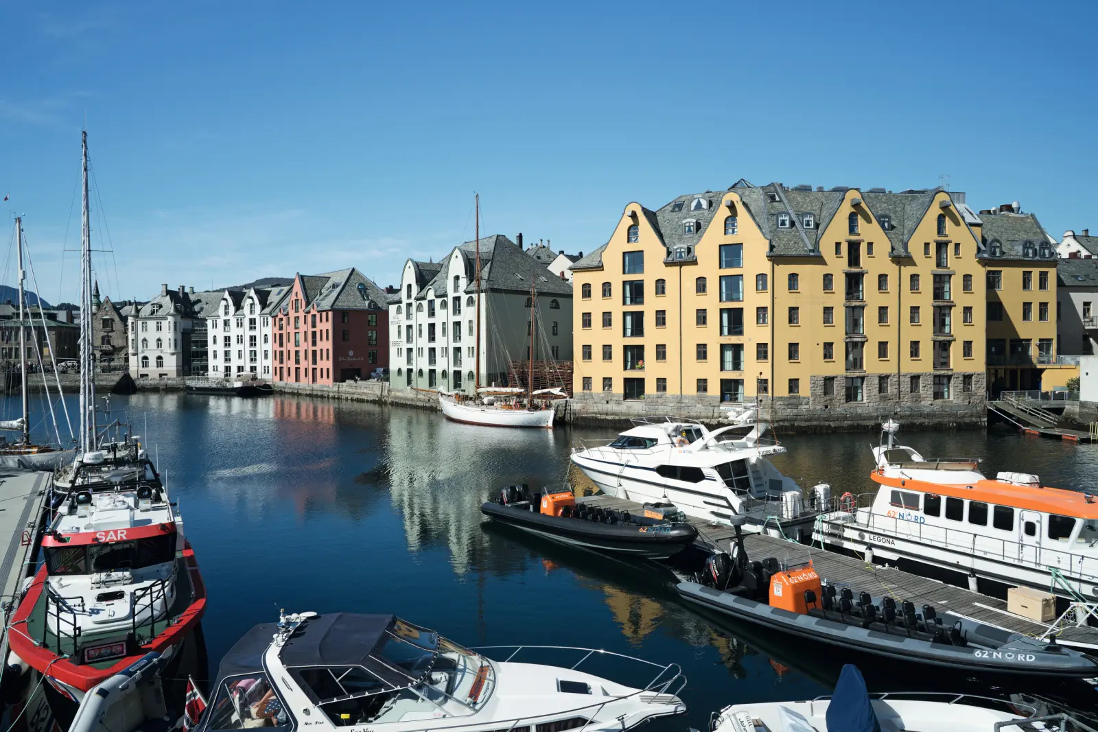 Case colorate sull'acqua con barche in un porto norvegese con cielo sereno.