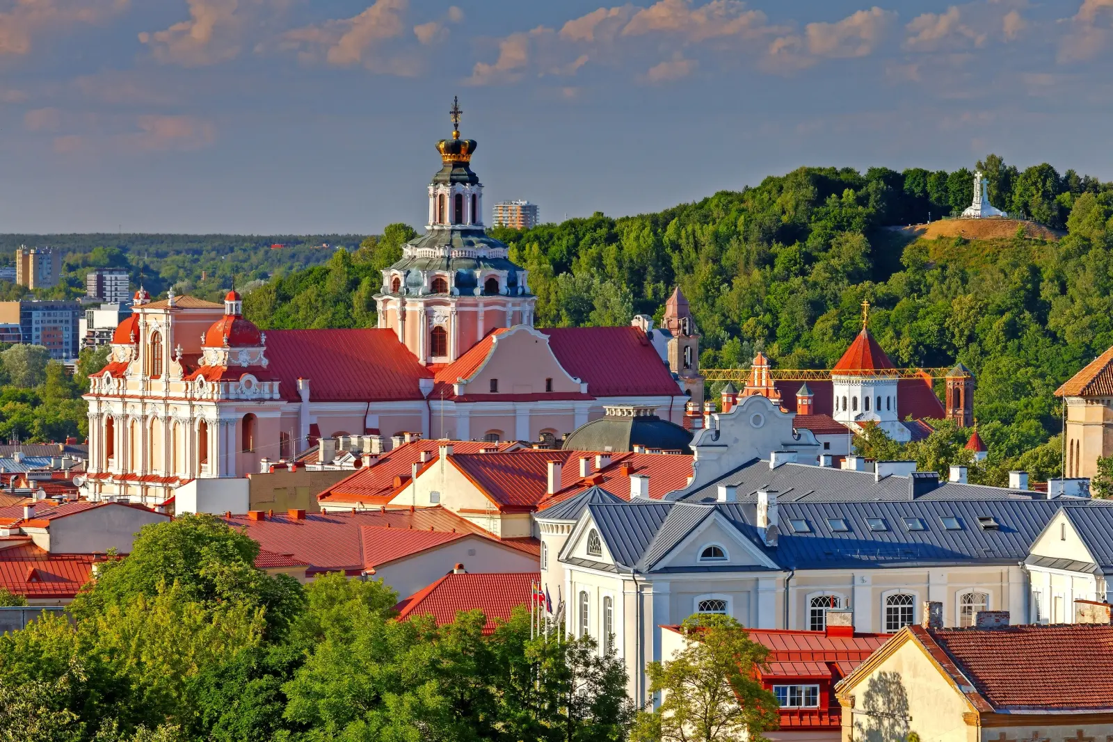 City view with churches and a green hill in the background under a clear sky.