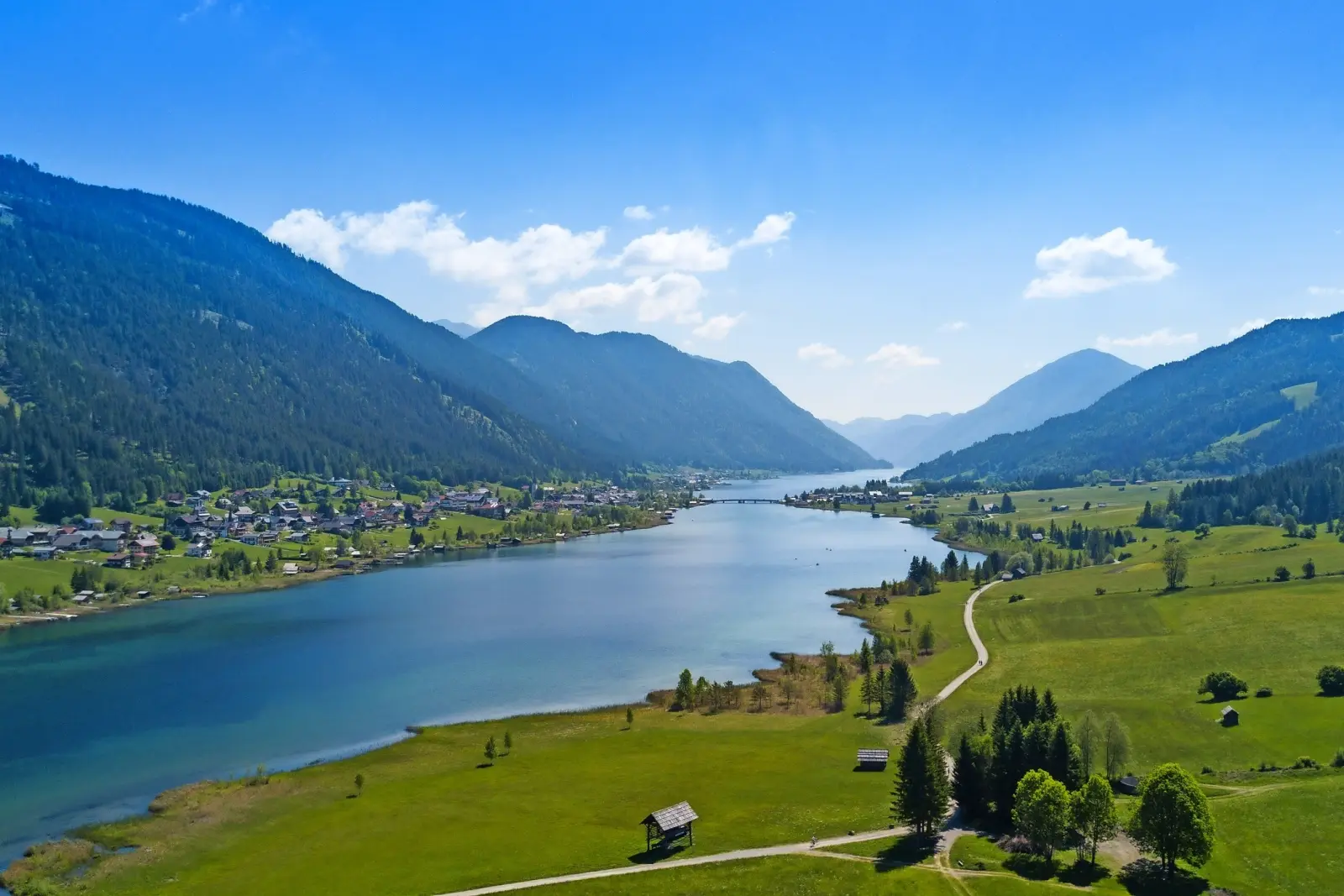 Mountain landscape with a lake and a village in the valley under a clear sky.
