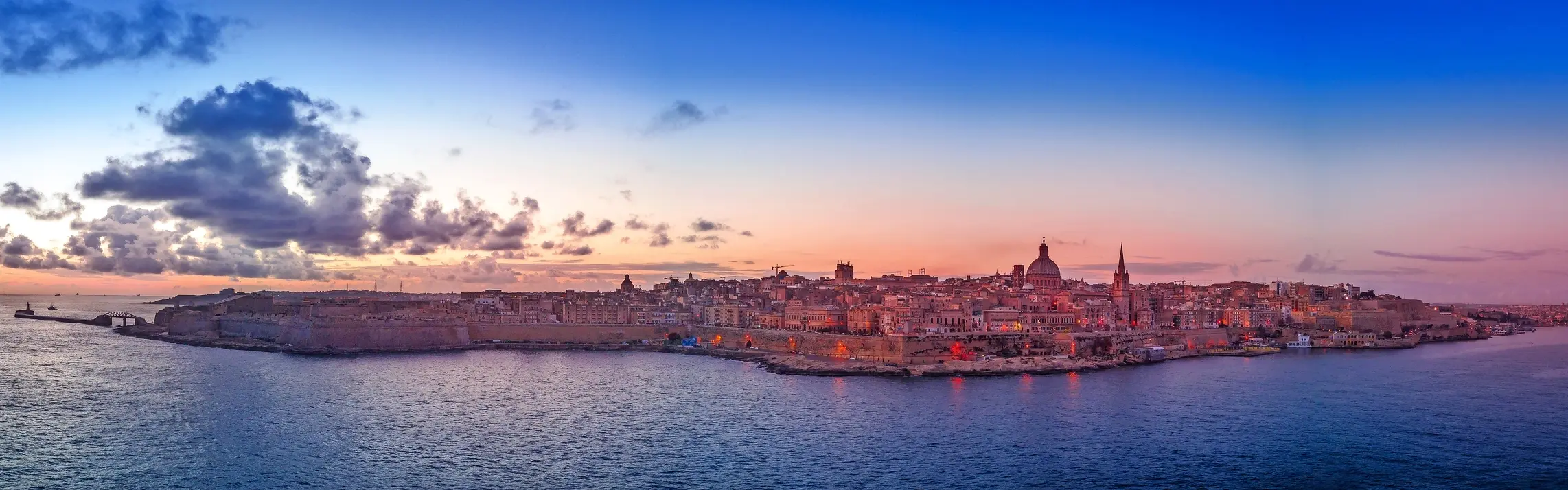 Vista panoramica di La Valletta al tramonto, sopra il mare.