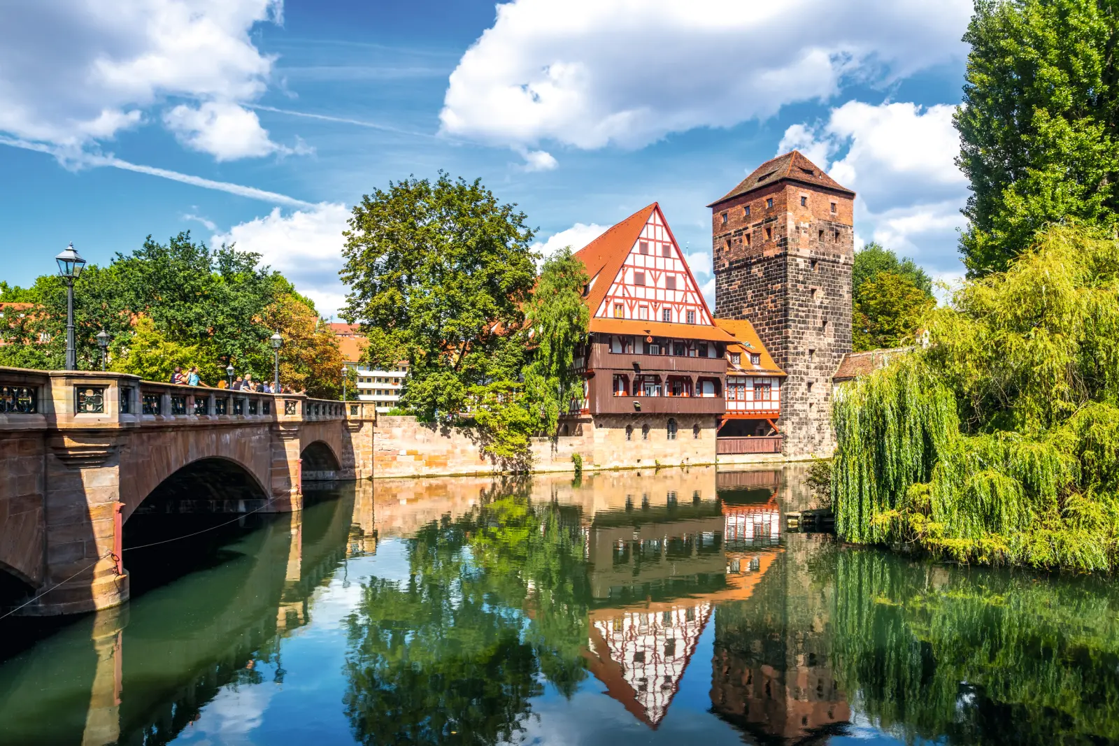 Maison à colombages et tour au bord du fleuve à Nuremberg, sous un ciel bleu
