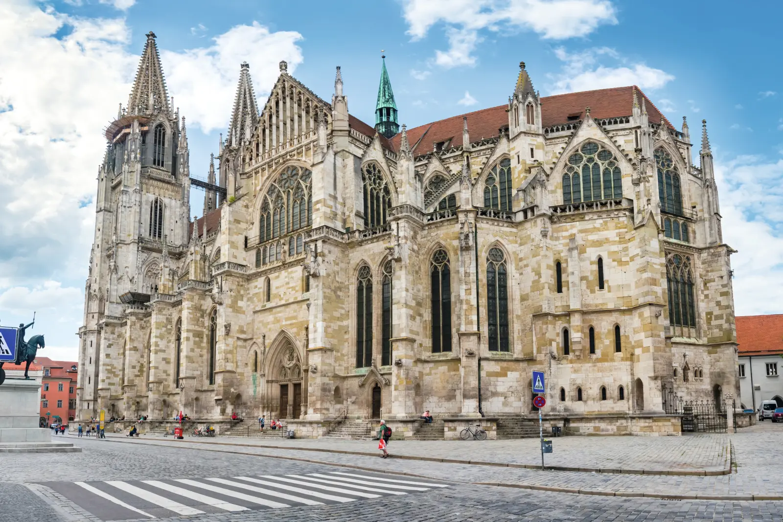 Gothic cathedral under a blue sky with people on a cobbled street.