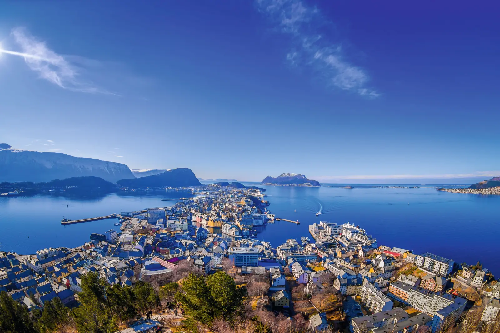 Luftaufnahme einer Küstenstadt mit Bergen und blauem Himmel.