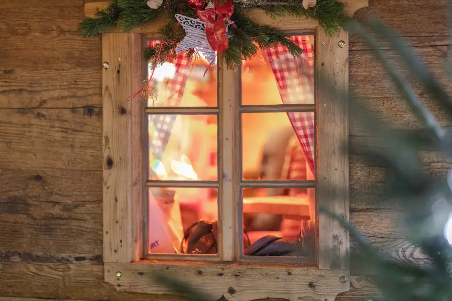 Illuminated window with a wooden frame and Christmas decorations.
