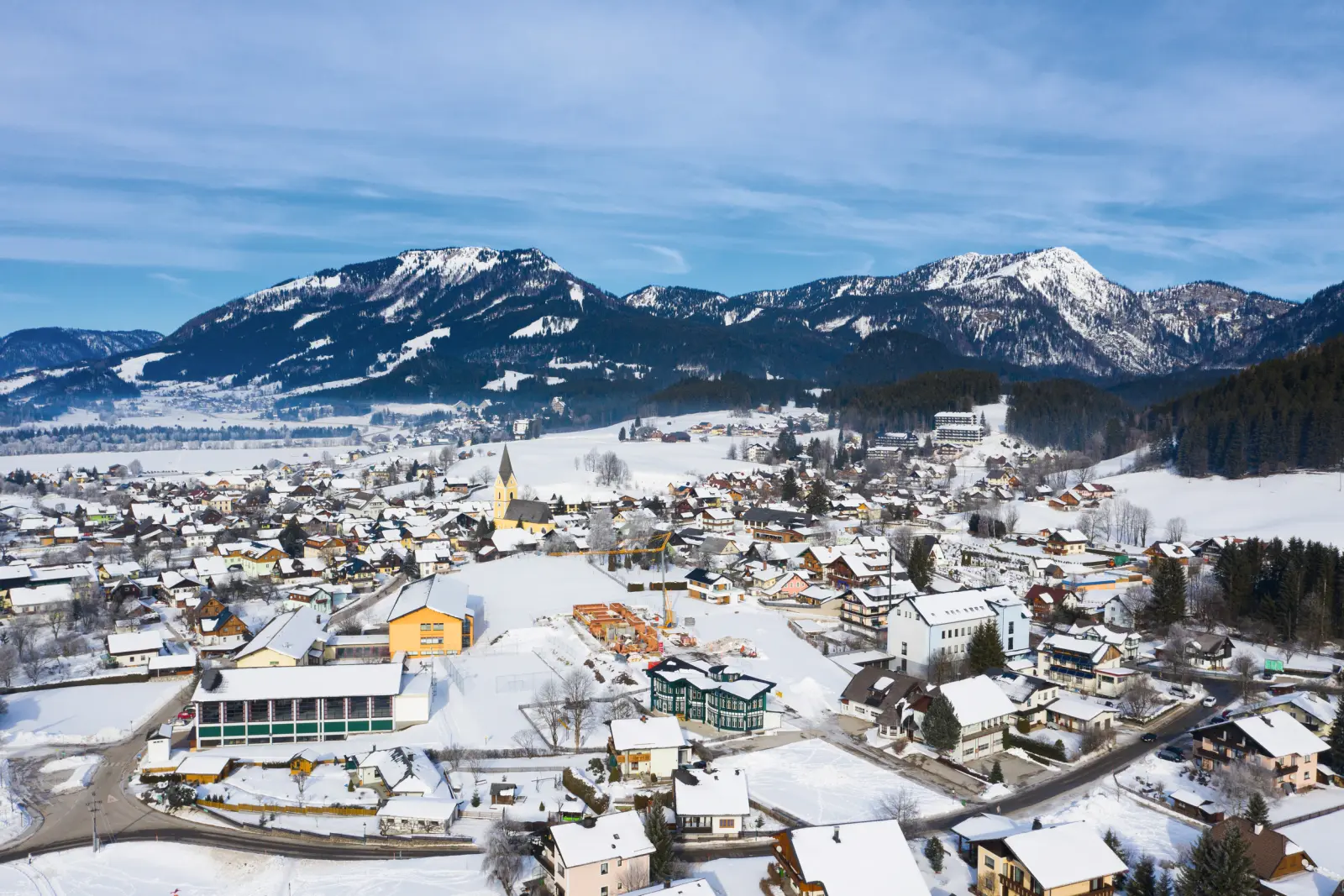 Città innevata in un paesaggio alpino con montagne sullo sfondo.