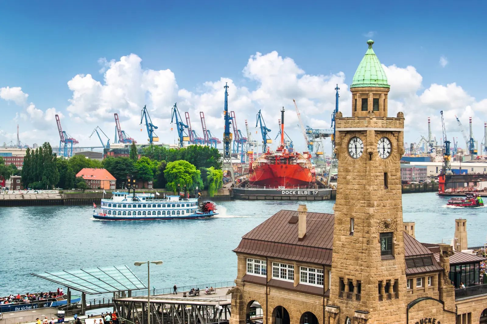Hafenansicht mit Turm und Schiff vor blauem Himmel im Hintergrund.